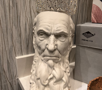 Bust of a bearded man looking stern while wearing a sparkly tiara.