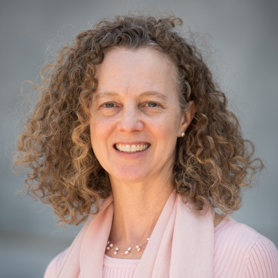 Image of Elizabeth Seaton with curly brown hair wearing a light pink scarf and sweater.
