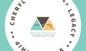 A white circle on a teal background contains the words "Cheryl Collins Legacy Scholarship" in dark brown around the perimeter with the KMA logo in the middle.