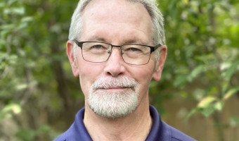 Cropped photo of James Locklear, a man with grayish white hair and glasses, wearing a dark blue polo shirt.